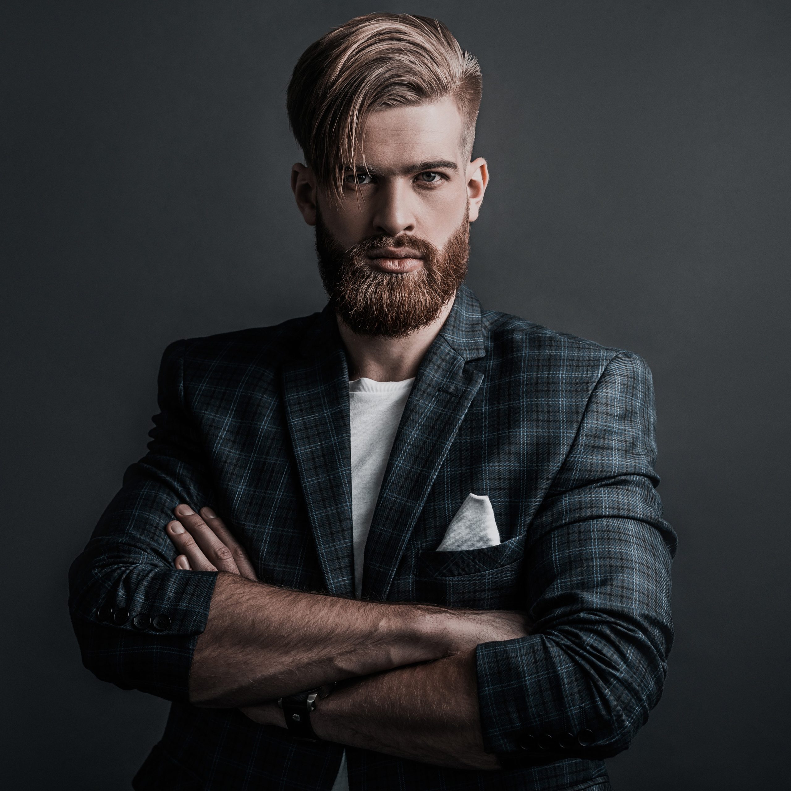 Man of your dreams! Handsome man keeping arms crossed and looking at camera while standing against grey background